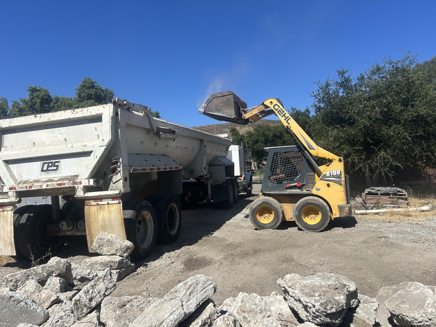 Skid-steer loading concrete debris into a dump truck for hauling