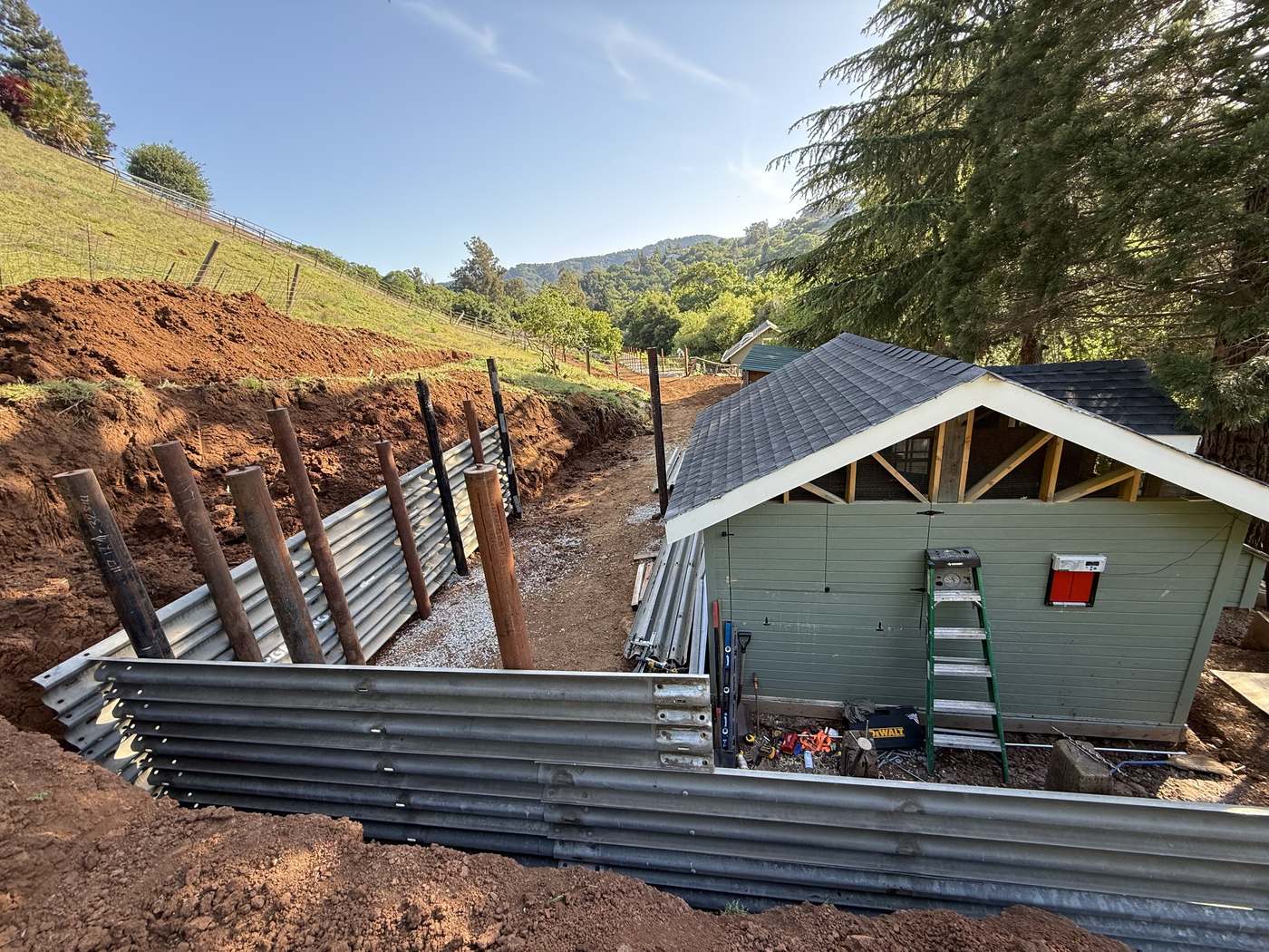 Steel I-beam retaining wall installation cut into a hillside