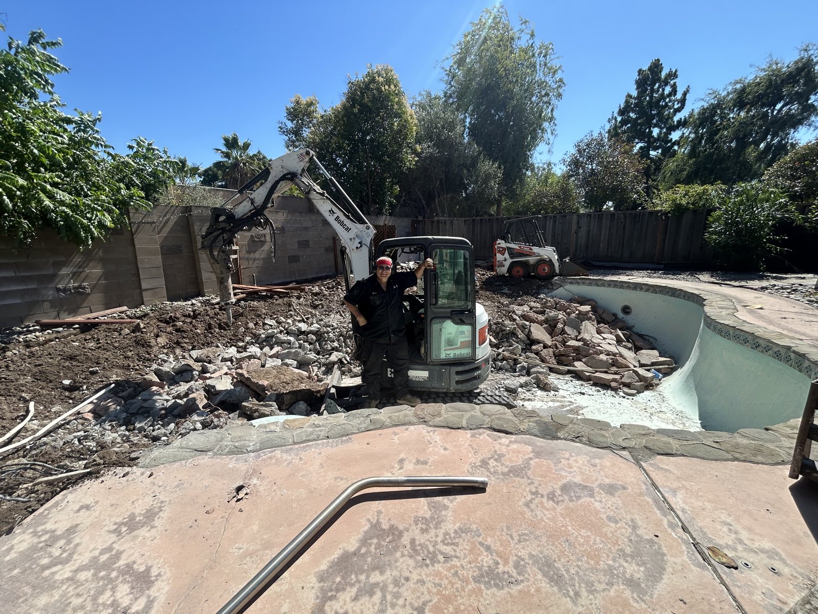 Terry standing next to his Bobcat excavator on an active job site